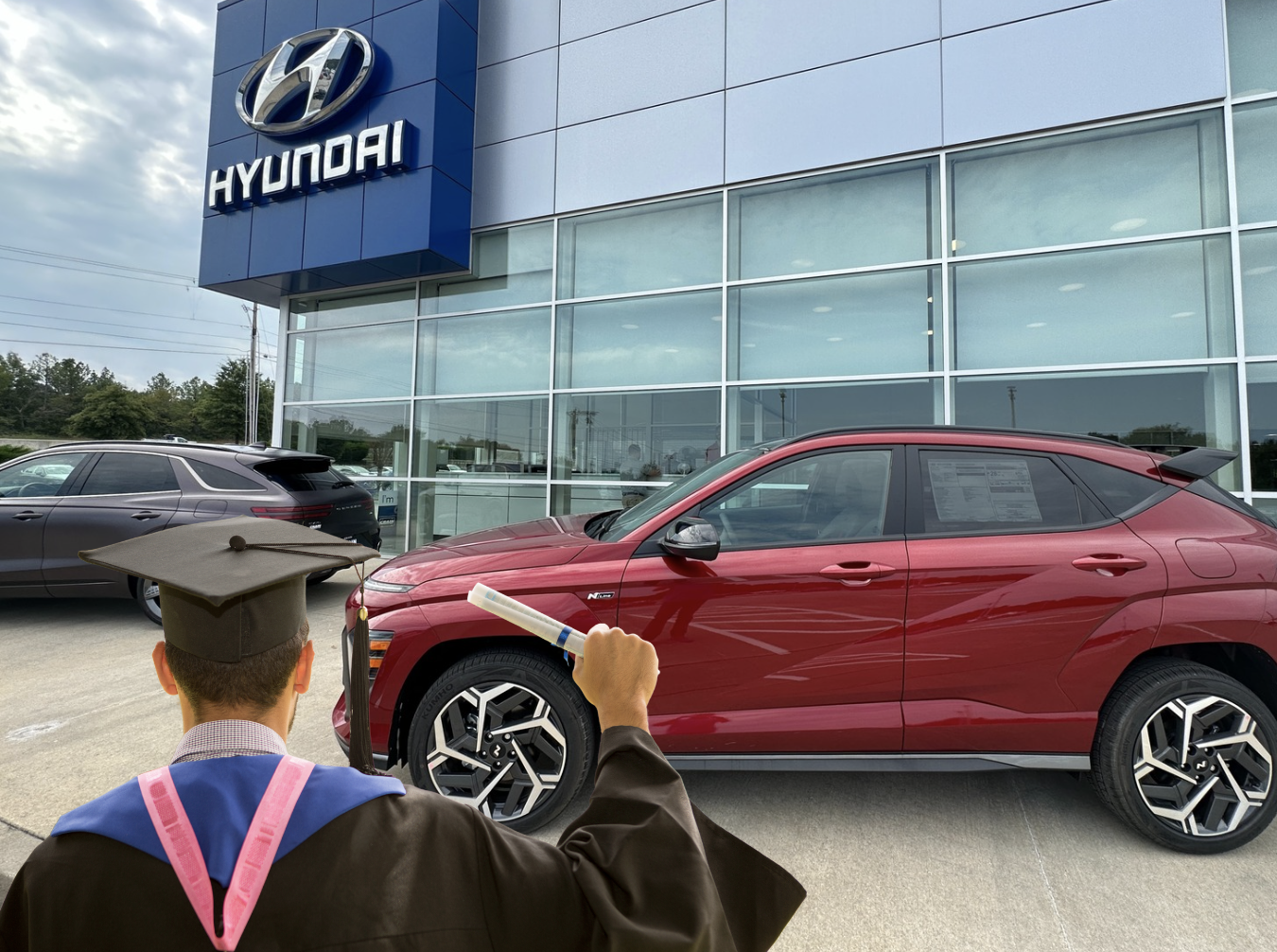 Graduate in cap and gown celebrates with a new red Hyundai SUV outside Crain Hyundai of Fayetteville.